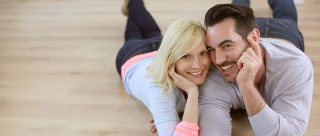 Sweet loving couple laying on wood flooring