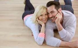 Sweet loving couple laying on wood flooring